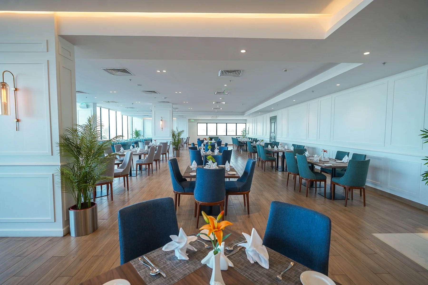 TAMARA’S dining room, with blue chairs, wooden tables and natural light